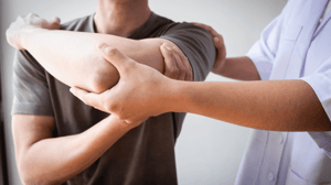 A man adjusts another man's shoulder.