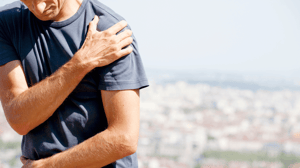 A man grips his shoulder in pain.