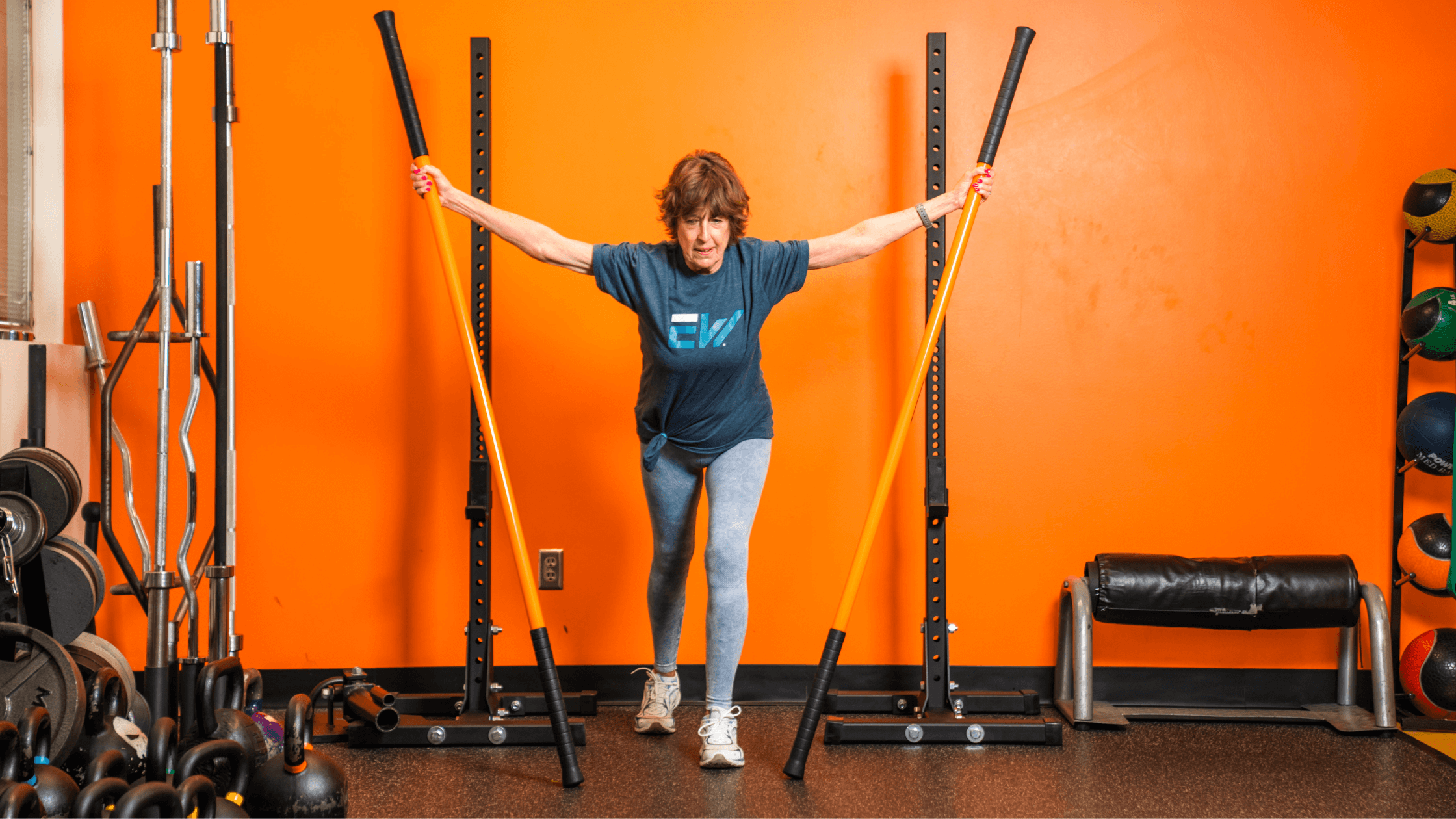 A woman walks with orange mobility sticks.