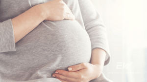 A pregnant woman cradles her stomach.