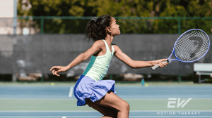 A young tennis player poises to hit the ball.