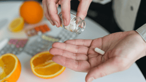 A person pours out one pill from a bottle into their hand.