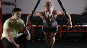 A man watches a woman pull resistance bands.