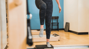 A woman stands on one foot.