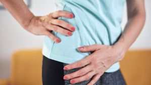 A woman grips her right hip in pain.