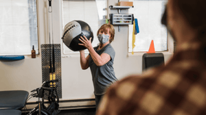 A woman holds up an exercise ball. 
