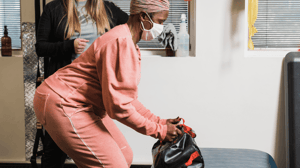A woman bends over to pick up a weighted bag.