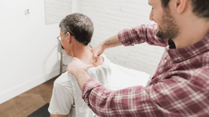 A man massages another man's shoulder and upper back. 
