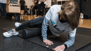 A woman rolls her leg on a foam roller. 