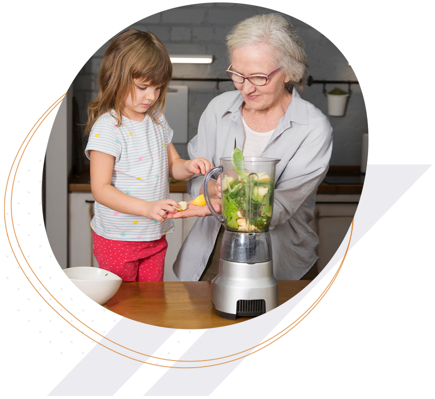 grandmother with granddaughter adding veggies to blender