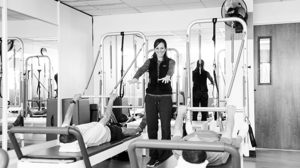 A woman leads a reformer Pilates class.