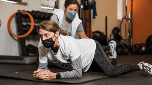 A woman lies on a mat in a plank position.