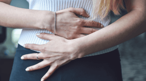 A woman places her hands on her abdomen.
