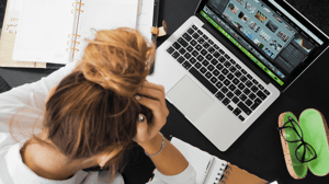 From above, a woman sits in a hunched position in front of her computer.
