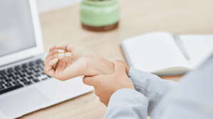 A male office employee massages his wrist.