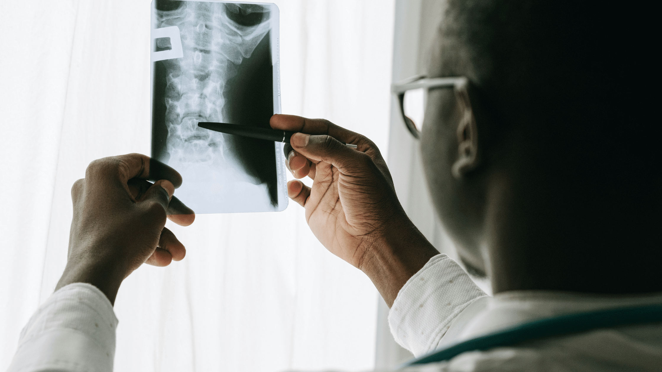 A doctor examines an X-ray by the light of a window.