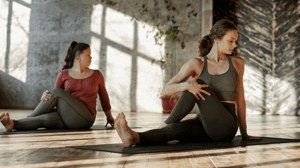 Two women stretch on yoga mats.