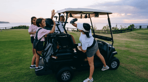 A group of kids high-fiving around a golf cart