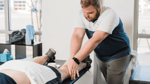 A man massages the leg of a person lying on a table.
